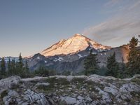 the mountain is covered with snow and has snow capped peak behind it at sunset as seen from a distance