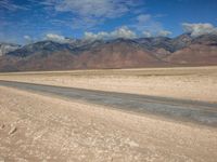 two motorcycles driving through an empty desert road near a mountain range with snow capped peaks