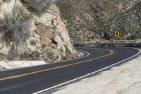 a lone motorcycle travels down the desert road in front of a mountain in this photo