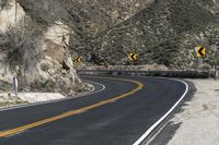 a lone motorcycle travels down the desert road in front of a mountain in this photo