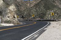 a lone motorcycle travels down the desert road in front of a mountain in this photo