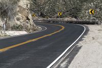 a lone motorcycle travels down the desert road in front of a mountain in this photo