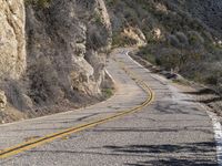 the motorcycle is moving through a curve on a mountain road along with trees in the foreground