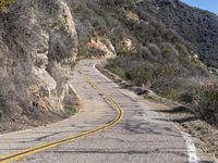 the motorcycle is moving through a curve on a mountain road along with trees in the foreground