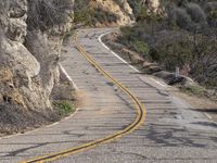 the motorcycle is moving through a curve on a mountain road along with trees in the foreground