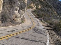 the motorcycle is moving through a curve on a mountain road along with trees in the foreground