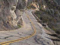 the motorcycle is moving through a curve on a mountain road along with trees in the foreground