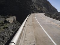 a long highway with two lanes and traffic lines on either side and in the distance are a high mountain