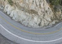 the road passes by an intricately curved mountain side curve, and one motorcycle is passing