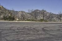 a view along a dirt road of an empty field and mountains in the distance of the scene