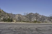 a view along a dirt road of an empty field and mountains in the distance of the scene