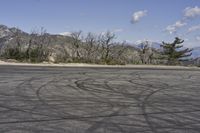 a view along a dirt road of an empty field and mountains in the distance of the scene