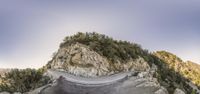 a motorcycle rider on a winding mountain road in the mountains with rocks and trees on the road