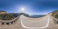 a 360 - view image of a mountain road on a sunny day with the sun shining