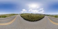 a curved road going down the mountain, with a sun in the middle of the view