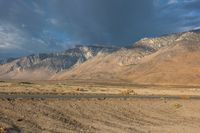 a lone motorbike is stopped at the end of an empty road in front of a mountain