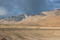 a lone motorbike is stopped at the end of an empty road in front of a mountain