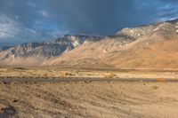 a lone motorbike is stopped at the end of an empty road in front of a mountain