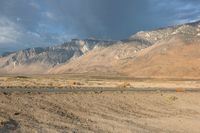 a lone motorbike is stopped at the end of an empty road in front of a mountain