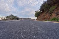 a motorcycle driving down a winding road under an overcast sky with some clouds in the distance