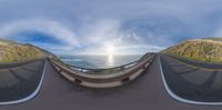 a fisheye lens shows the sea on a mountain road that is curved down the side