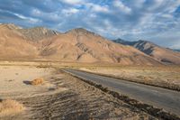 an empty road that has been paved near a mountainous mountain range on a sunny day