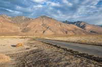 an empty road that has been paved near a mountainous mountain range on a sunny day