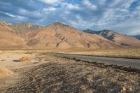 an empty road that has been paved near a mountainous mountain range on a sunny day