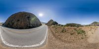 a fish eye lens view of a mountain road with the sun in the sky above