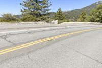 the side of a road on a mountain with mountains in the background and two yellow lines that are going in two opposite directions