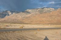 the desert with a lone road is shown in the foreground and mountains in the distance