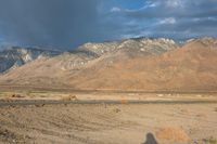 the desert with a lone road is shown in the foreground and mountains in the distance