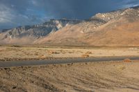 the desert with a lone road is shown in the foreground and mountains in the distance