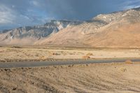 the desert with a lone road is shown in the foreground and mountains in the distance