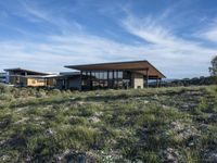 a small modern home in the middle of a desert landscape with grass in front of it