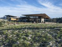 a small modern home in the middle of a desert landscape with grass in front of it