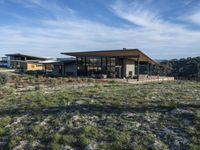 a small modern home in the middle of a desert landscape with grass in front of it