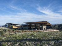 a small modern home in the middle of a desert landscape with grass in front of it