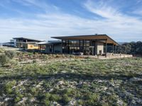 a small modern home in the middle of a desert landscape with grass in front of it