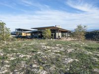 a small modern home in the middle of a desert landscape with grass in front of it