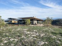 a small modern home in the middle of a desert landscape with grass in front of it