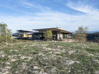 a small modern home in the middle of a desert landscape with grass in front of it