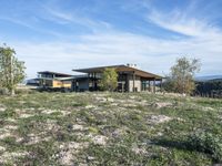 a small modern home in the middle of a desert landscape with grass in front of it