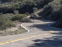 a skateboarder is riding on an empty road in the mountains near a street sign