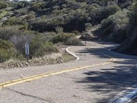 a skateboarder is riding on an empty road in the mountains near a street sign