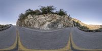 fisheye lens shot of a mountaintop and winding road in california mountains with trees on the rock