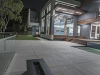 view of a large modern house from the pool at night with modern outdoor area on the opposite side