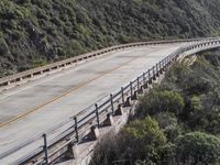 a motorcycle is driving on the road near the mountains of california's coast guard