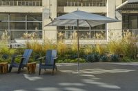 some tables and chairs sit in front of a building with an umbrella on one side