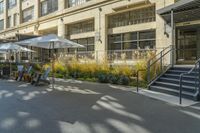 some tables and chairs sit in front of a building with an umbrella on one side